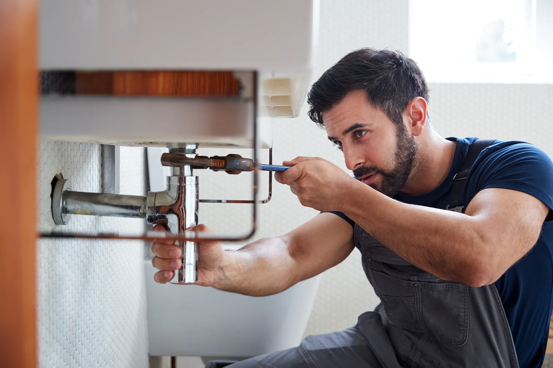 Professional plumber working on pipes